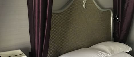 A neatly made bed with white linens, a headboard with a textured pattern, and a bedside table with a lamp.