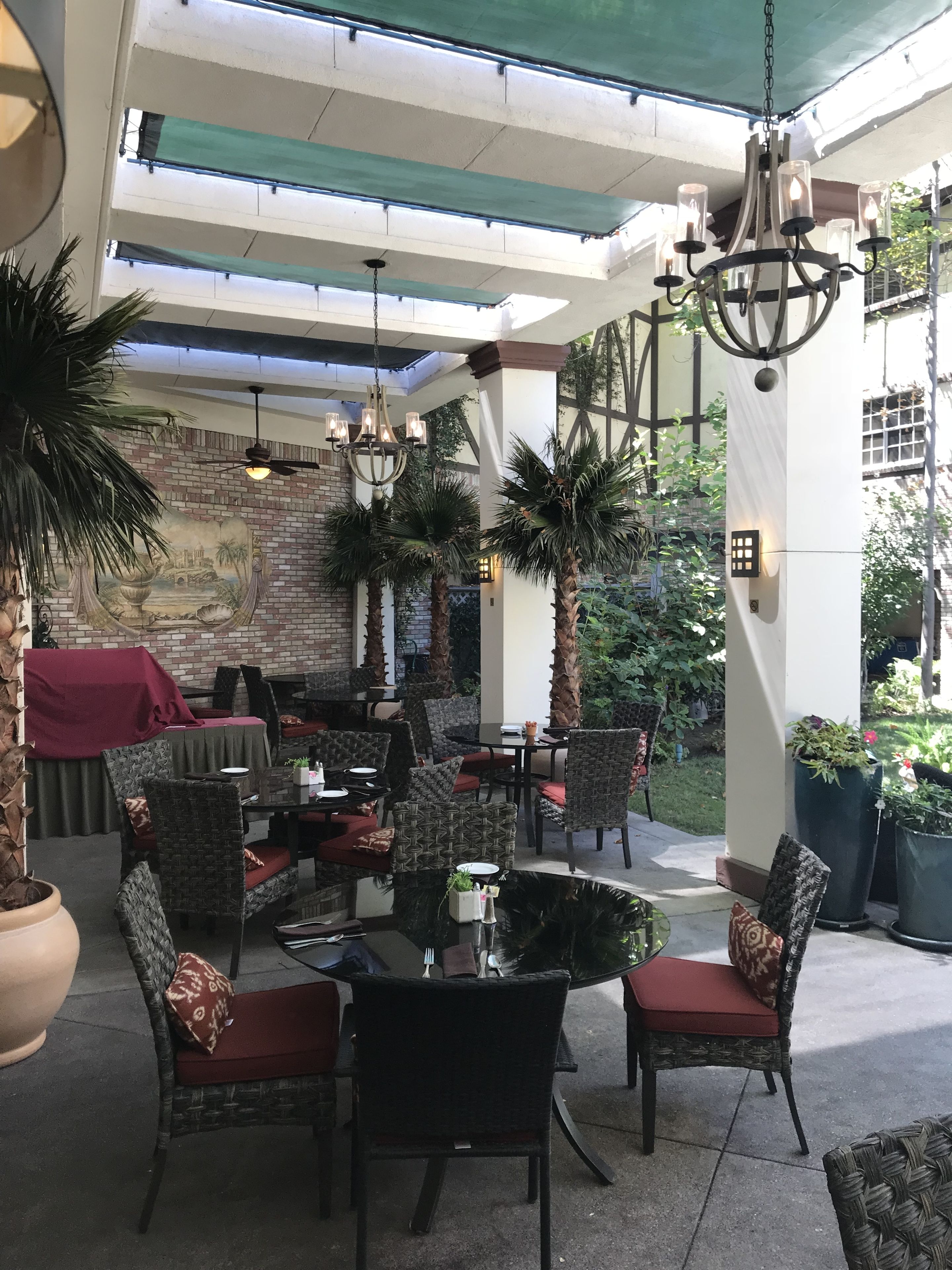 An outdoor patio area with wicker furniture, a central table, and hanging lights.