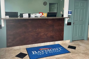 Un mostrador de recepción con un tapete azul que dice "Baymont Inn & Suites" y un reloj en la pared.