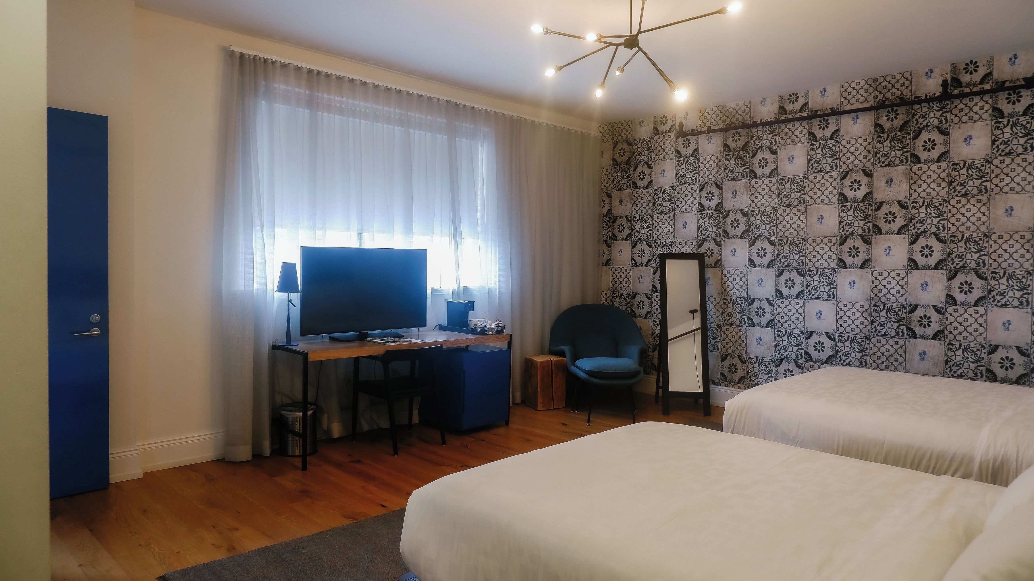 Habitació d'hotel amb escriptori, ordinador, cadira, llit i mirall.