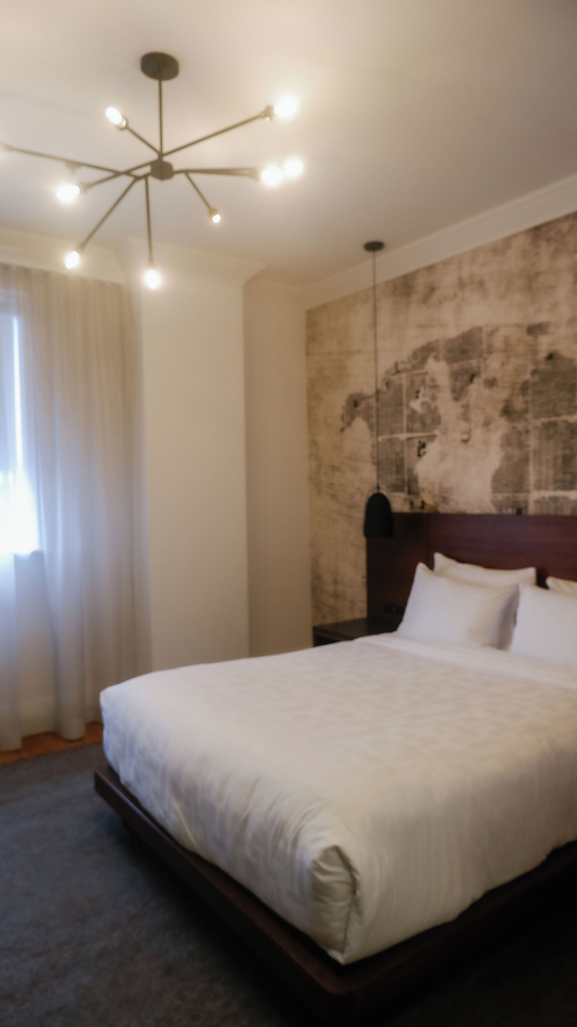 Et moderne hotelværelse med en stor seng, en væg med en spændende struktur og en moderne lysekrone.