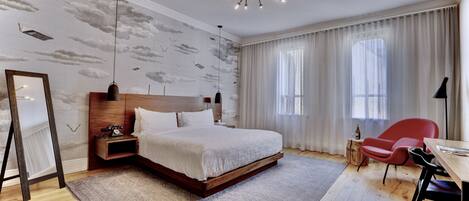 Una camera da letto moderna con un letto grande, un comodino in legno, una sedia rossa e una scrivania con una lampada.