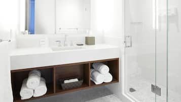 Une salle de bain moderne avec un lavabo blanc, un miroir et une douche en verre.