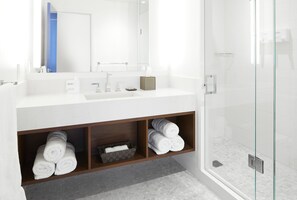 A modern bathroom with a white sink, mirror, and glass shower enclosure.