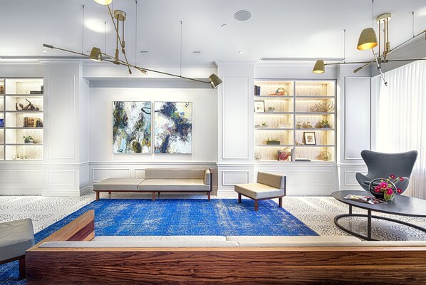 Relax in this stylish living room with a blue patterned rug, a coffee table, a gray armchair, and a beige sofa.
