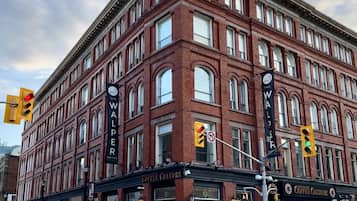 A historic red brick building with multiple stories, featuring large windows and a prominent sign for 'The Waler Hotel'.