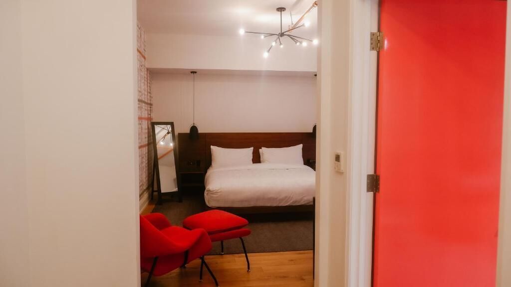 A bedroom with a wooden headboard, a white bed, and a red door.
