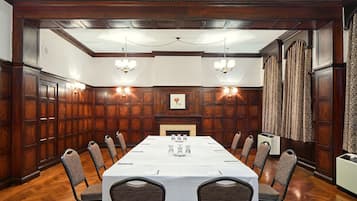 A conference room with a long table, chairs, and a fireplace.