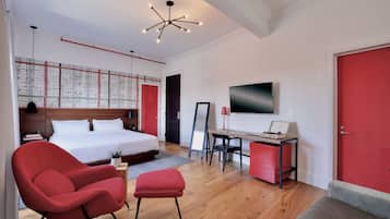 Una camera da letto moderna con un letto, una scrivania, una sedia rossa e una televisione.