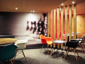 A modern meeting room with a large wall mural, round tables, and colorful chairs. - ibis Montpellier Centre Comédie (Montpellier)