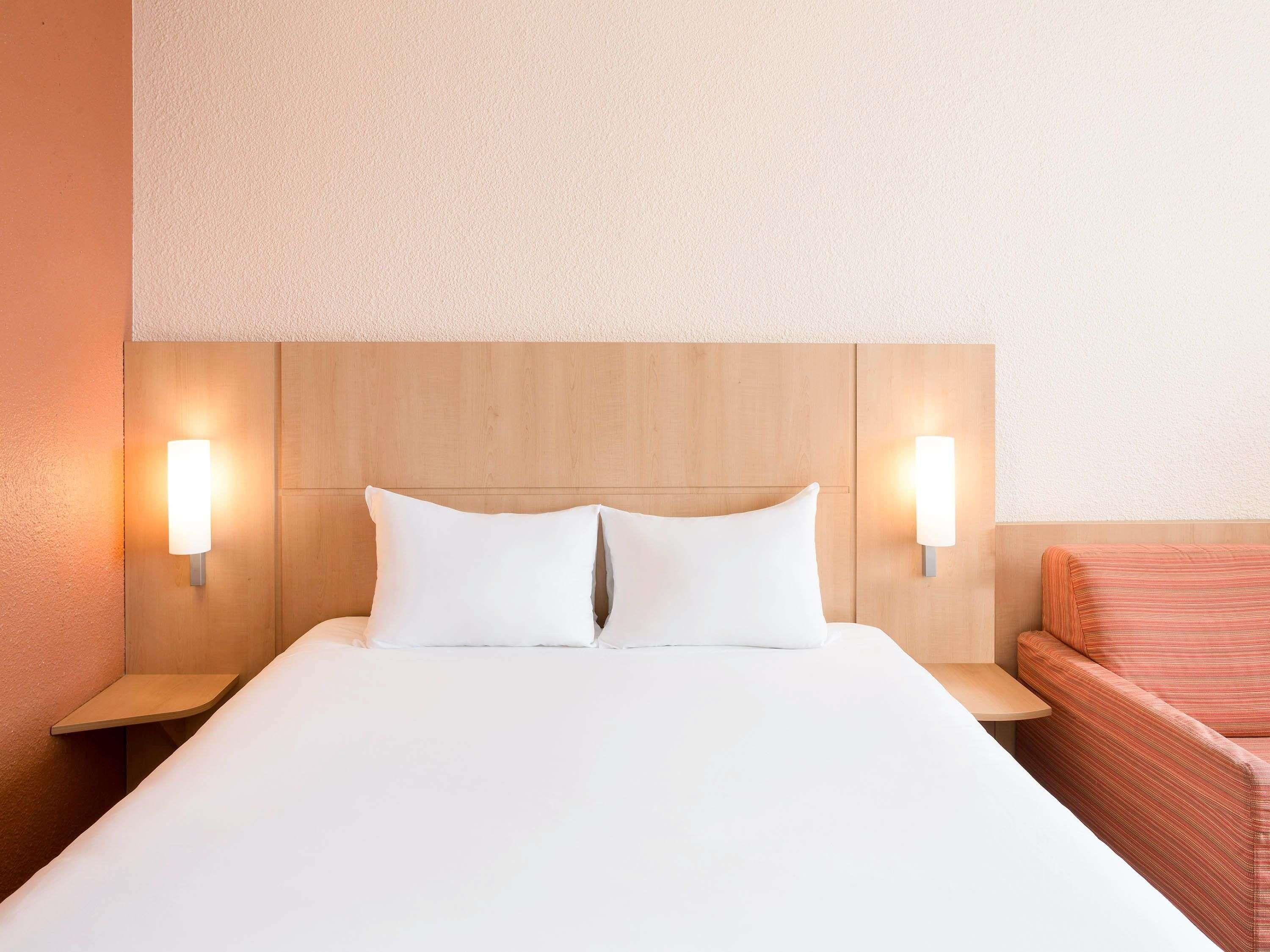 A hotel room with a large bed, two bedside tables, and a small sofa.