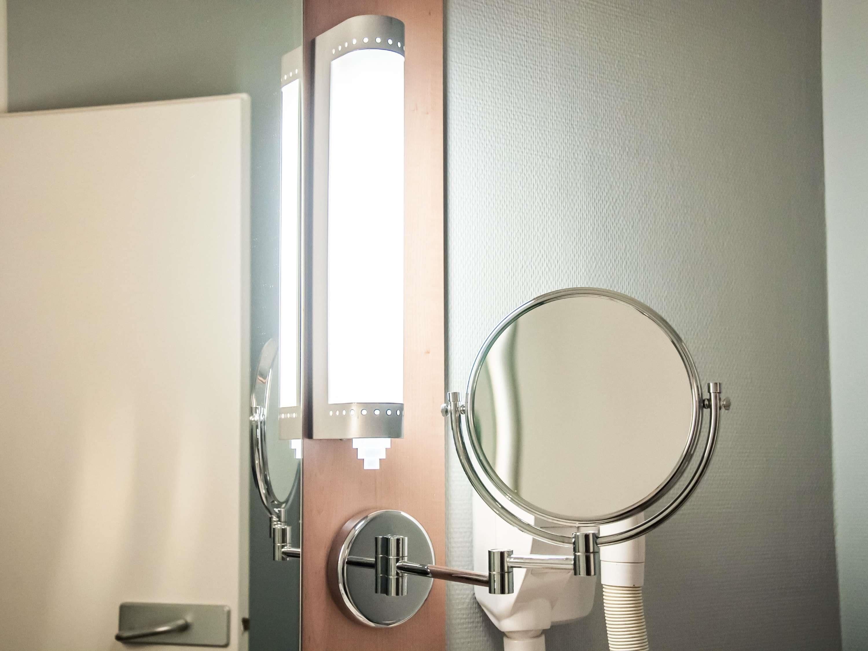 A bathroom with a mirror, a light fixture, and a door.