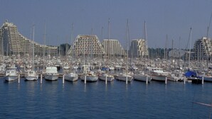 A marina with numerous boats docked, surrounded by buildings with a modern architectural style.