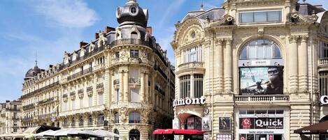 A historic building with ornate architecture, a prominent dome, and a large advertisement for 'eleom'.