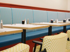A restaurant with booths and tables, each with cutlery and salt shakers.