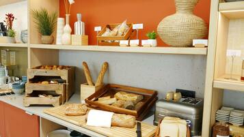 Une vitrine de boulangerie présentant une variété de pains, de pâtisseries et de pots de confitures et de pâtes à tartiner.