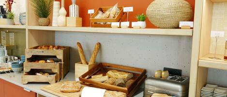 Een bakkerijdisplay met verschillende broden, gebakjes en potten met beleg.