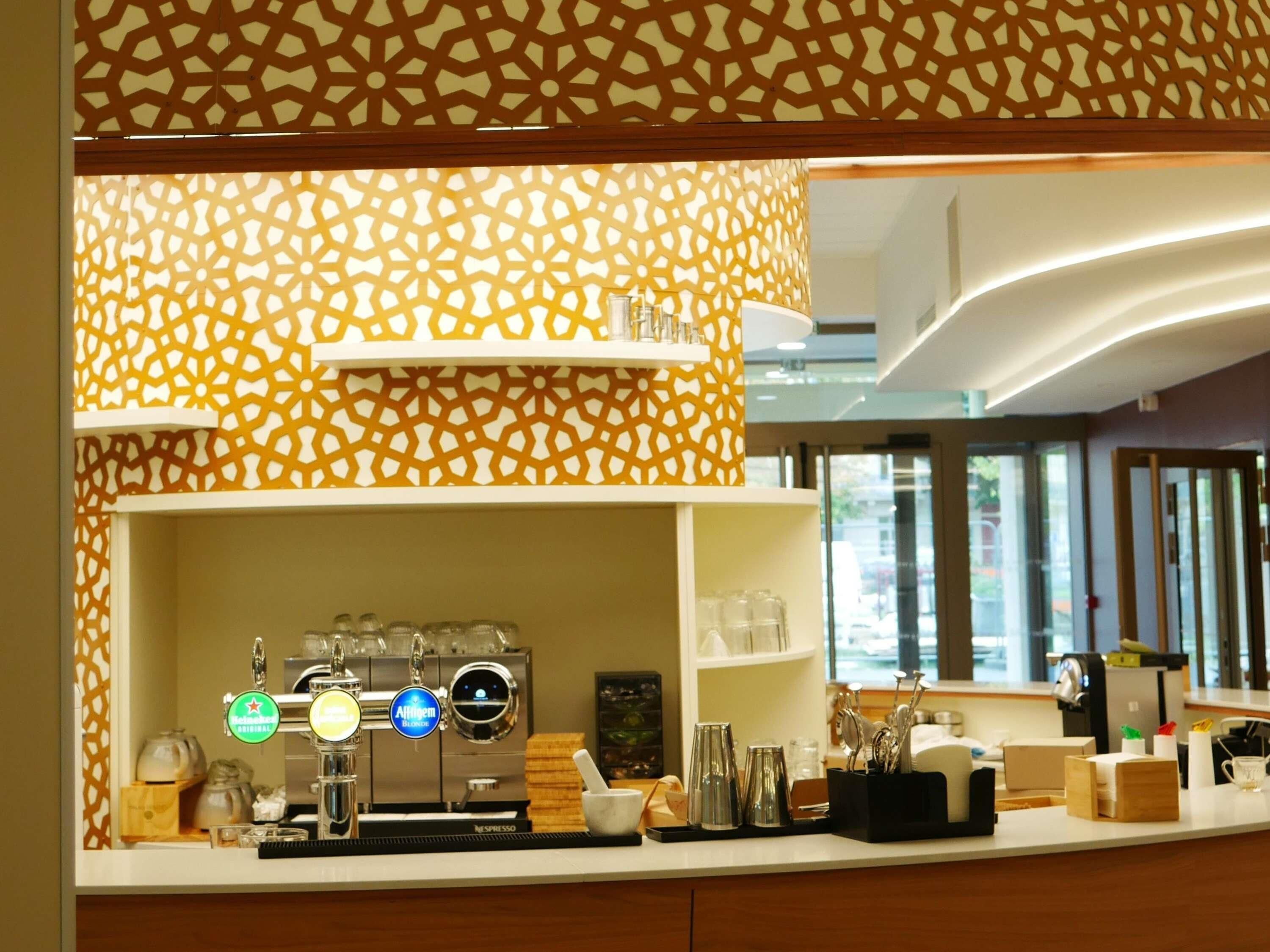 A modern kitchen with a coffee machine, a patterned wall, and a view of the outside.