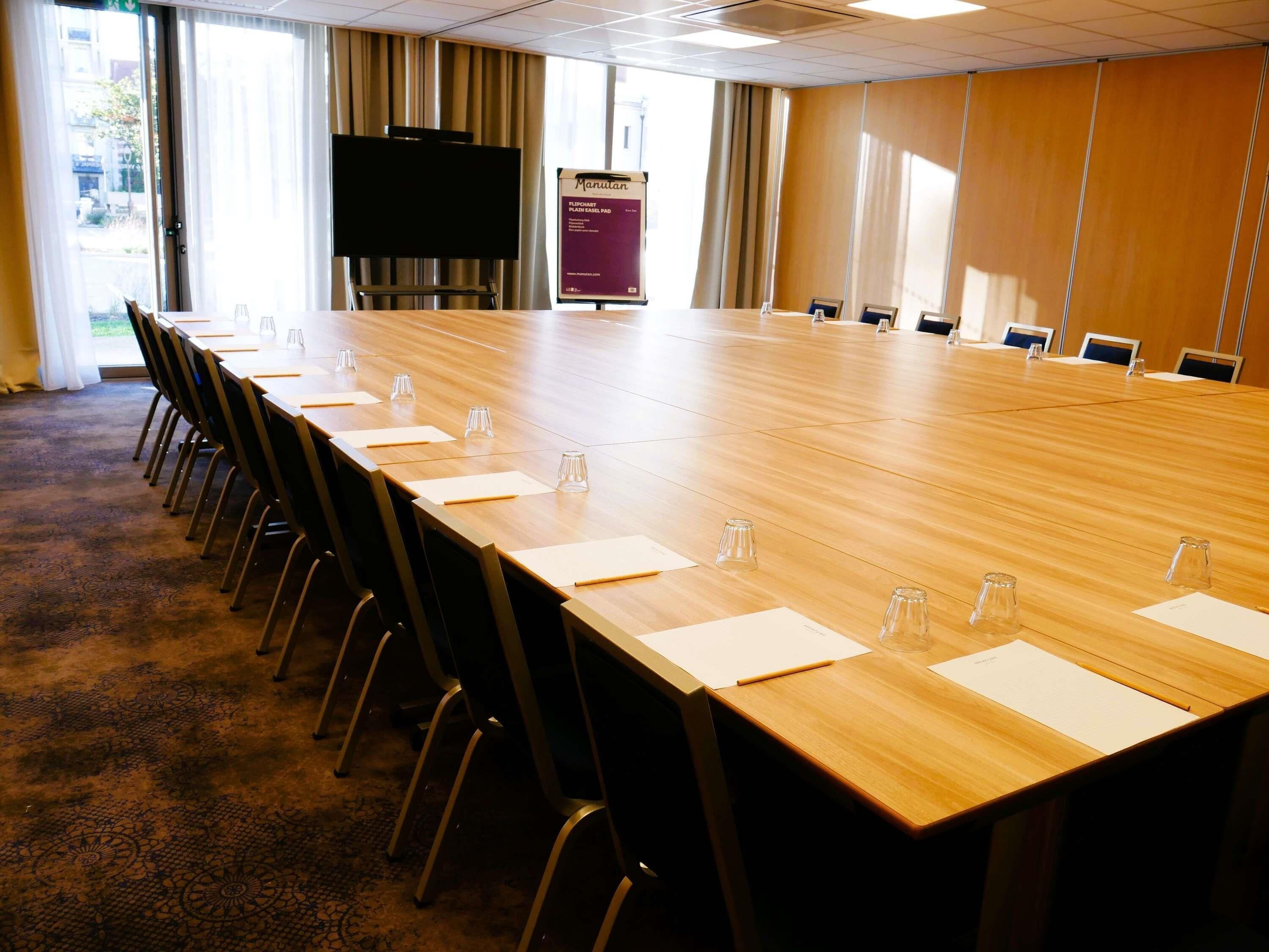 A conference room with a long table, chairs, a podium, and a large window.