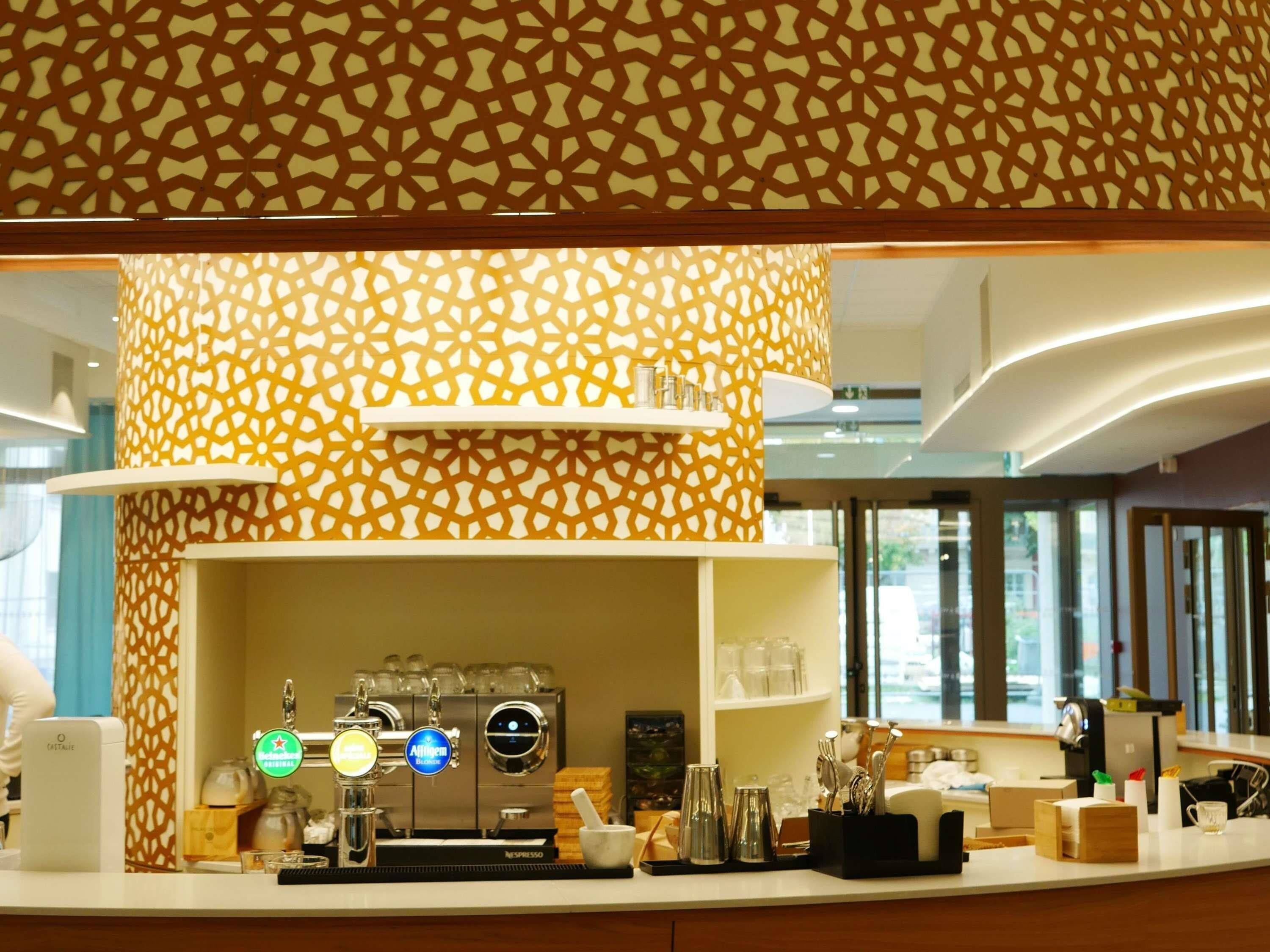 A modern bar area with a coffee machine, bar tools, and a patterned wall.