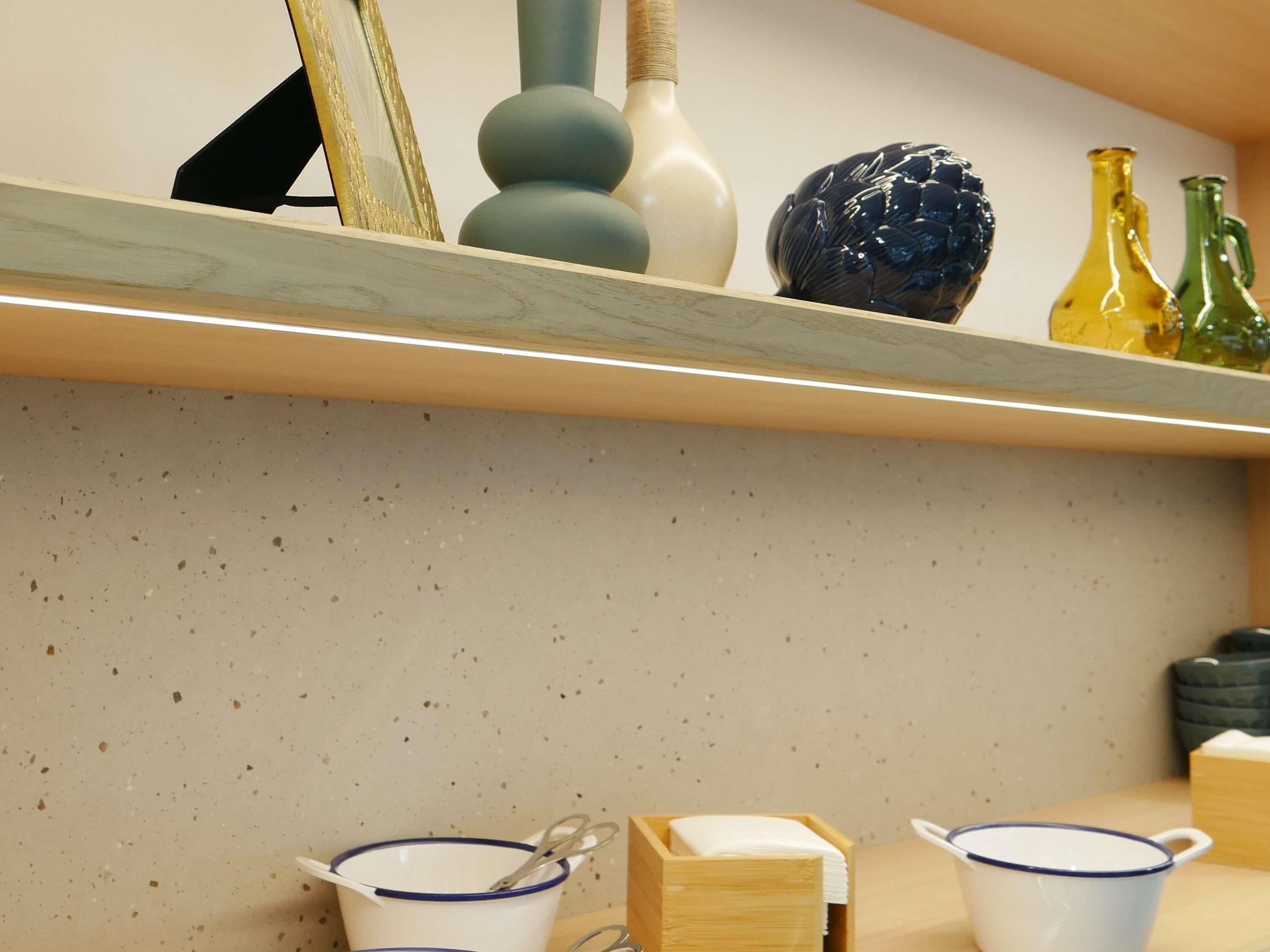 A kitchen shelf with various ceramic items, including a blue and white bowl, a white vase, and a blue decorative object.