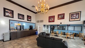 A hotel lobby with a coffee station, seating area, and framed pictures on the walls.