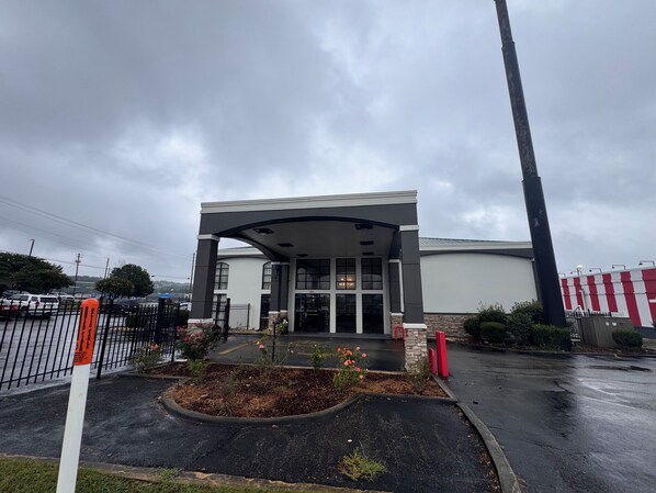 A building with a covered entrance, a parking lot, and a storm drain.