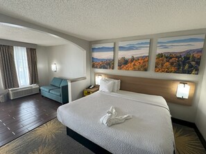 A hotel room with a large bed, a sofa, a desk, and a window with curtains. - Days Inn & Suites by Wyndham Tuscaloosa - Univ. of Alabama (Tuscaloosa)