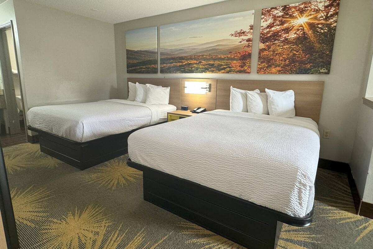 Ein Hotelzimmer mit zwei Betten, einem Nachttisch, einem Telefon und einer Wandleuchte.