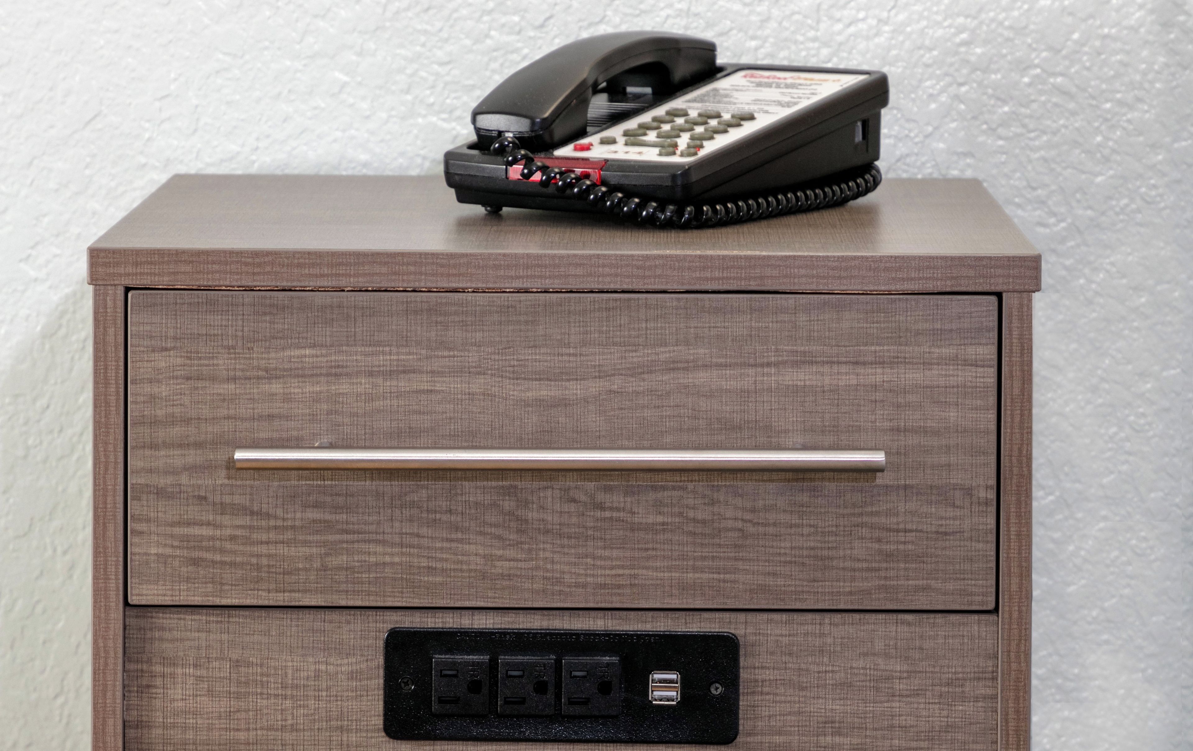Un meuble en bois avec un téléphone posé dessus et un tiroir doté d’un port USB.