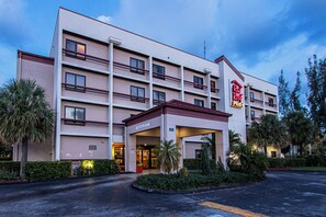 A multi-story hotel with a flat facade, a covered entrance, and a parking lot.