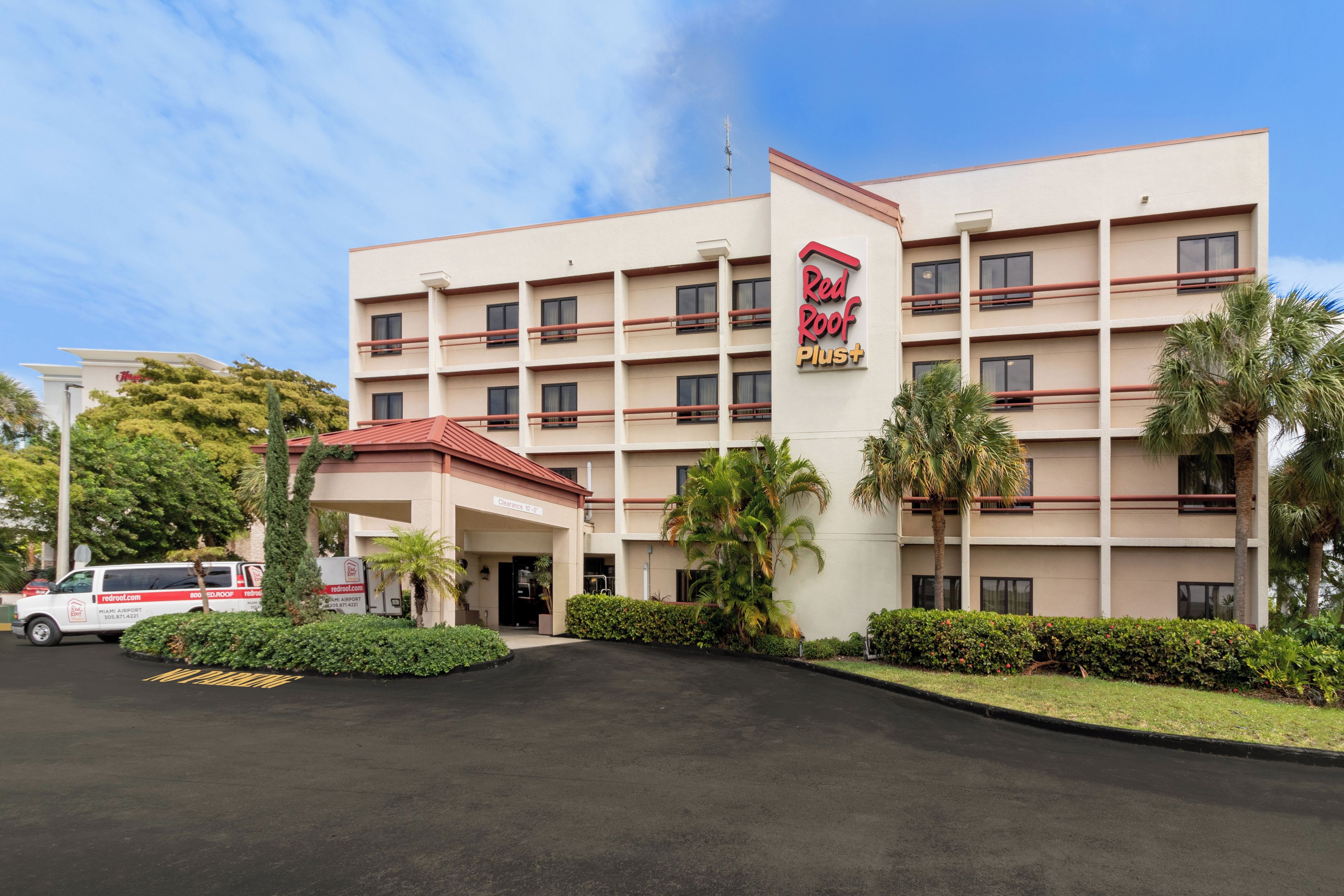 A Red Roof Plus hotel with a central entrance, multiple floors, and a parking area.