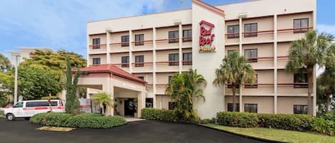 Hotel Red Roof Plus com entrada central, vários andares e área de estacionamento.