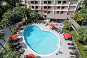 An aerial view of a hotel with a swimming pool surrounded by lounge chairs and umbrellas. - Red Roof Inn PLUS+ Miami Airport (Miami)
