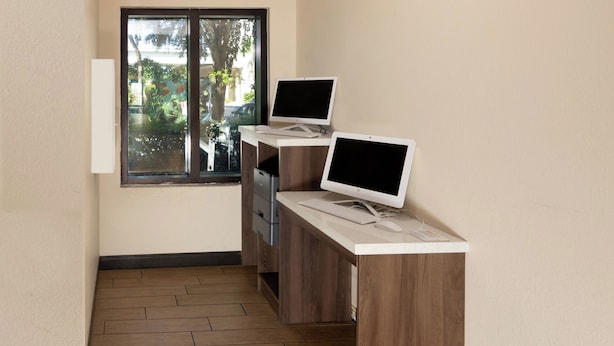A room with a wooden desk, two monitors, a keyboard, and a mouse. - Red Roof Inn PLUS+ Miami Airport (Miami)