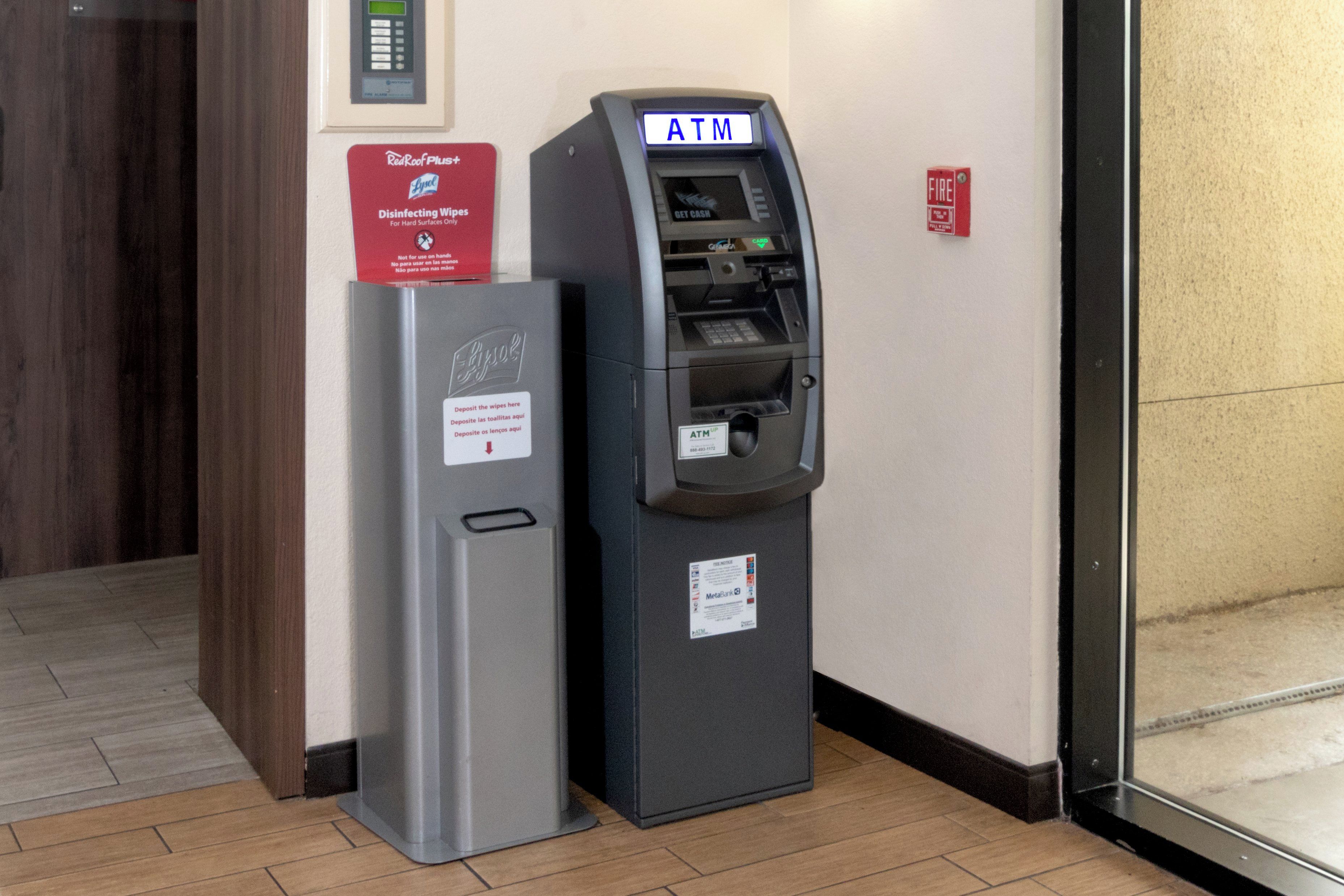 An ATM machine and a refrigerator with a sign indicating disinfecting wipes for hard surfaces.