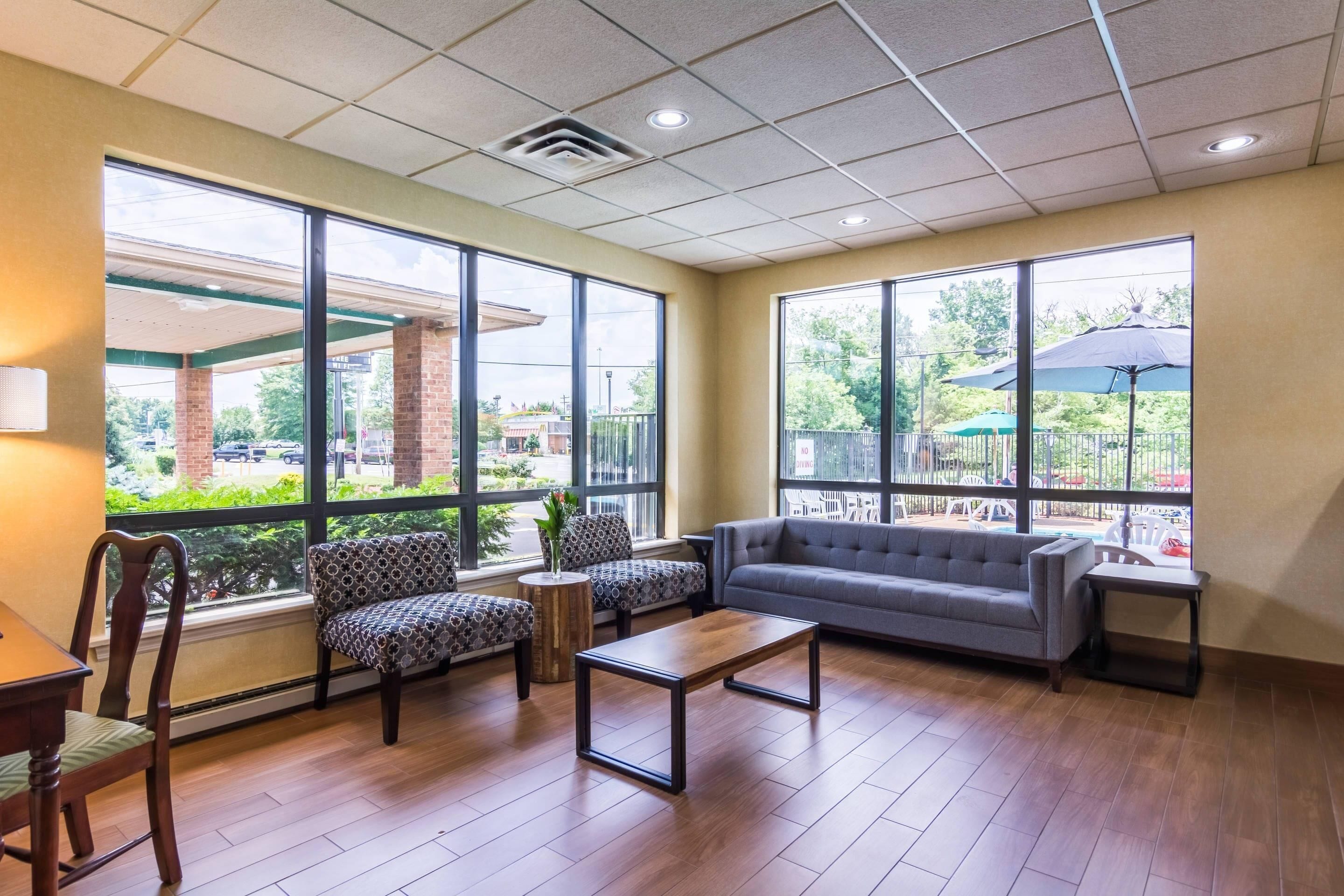 A spacious indoor area with a sofa, chairs, a coffee table, and large windows offering views of the outdoors.