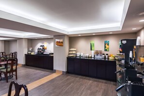 A hotel breakfast area with a counter, seating, and various food and beverage stations. - Quality Inn Manassas (Manassas)