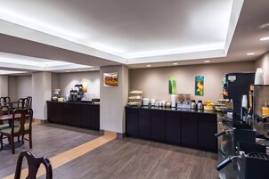 Un comedor de hotel con mostrador, asientos y varias estaciones de comida y bebidas.