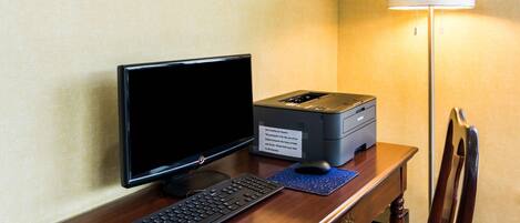 A hotel desk with a computer, keyboard, and printer.