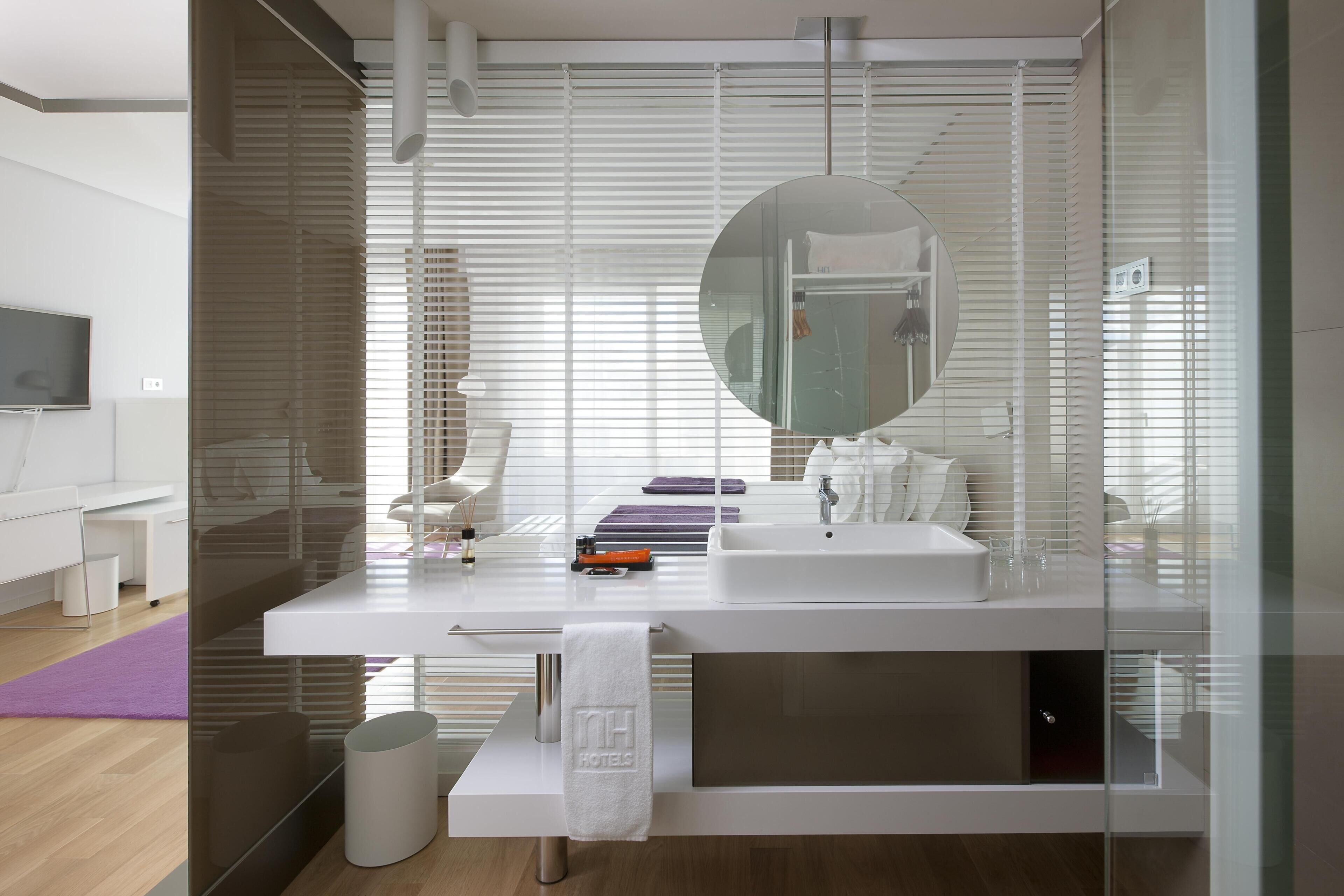 Ein modernes Badezimmer mit Glastrennwand, großem Spiegel, weißem Waschbecken und Handtuchhalter.
