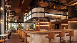 Un espace bar moderne doté d’un comptoir incurvé, de nombreux tabourets et d’une grande variété de bouteilles et de verres.