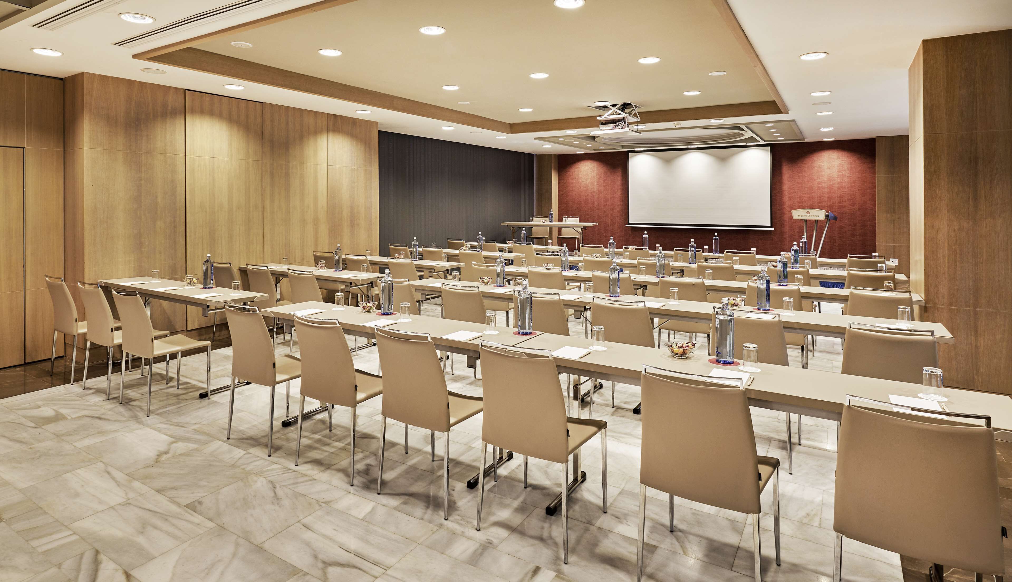 A conference room with multiple tables and chairs, equipped with water bottles and nameplates.