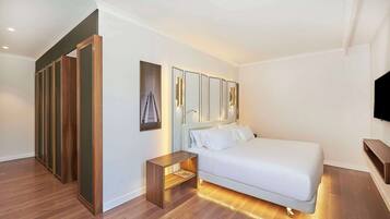 Camera d'albergo moderna con un letto grande, un armadio in legno, un piccolo comodino e una TV a muro.