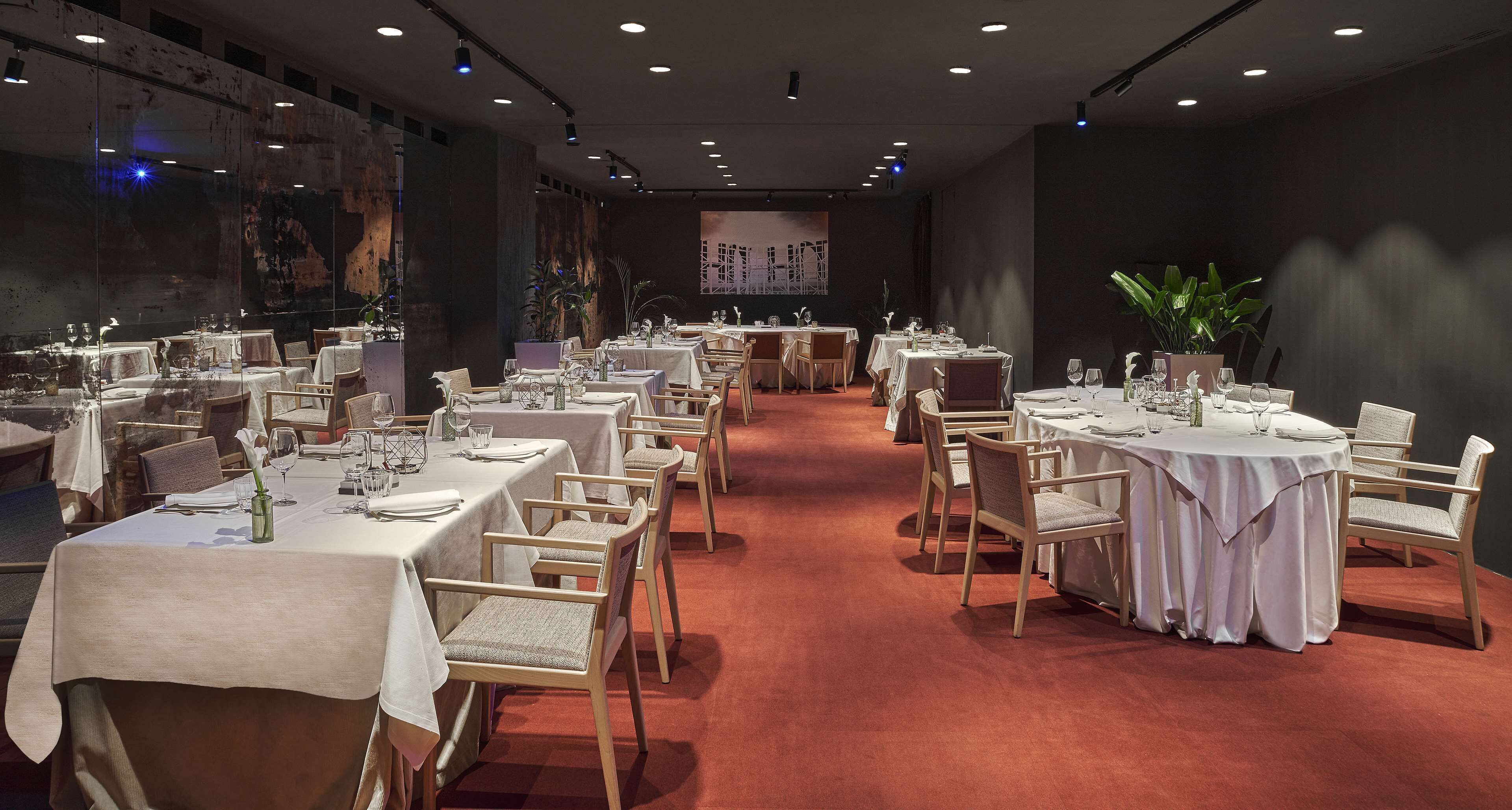 A banquet hall with multiple round tables set for dining, each with white tablecloths and chairs.