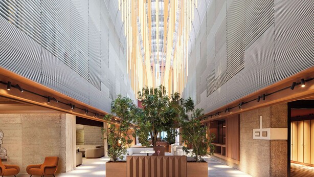 Un hall d’entrée spacieux avec un espace salon central, un plafond haut orné d’un motif original et un comptoir d’accueil.