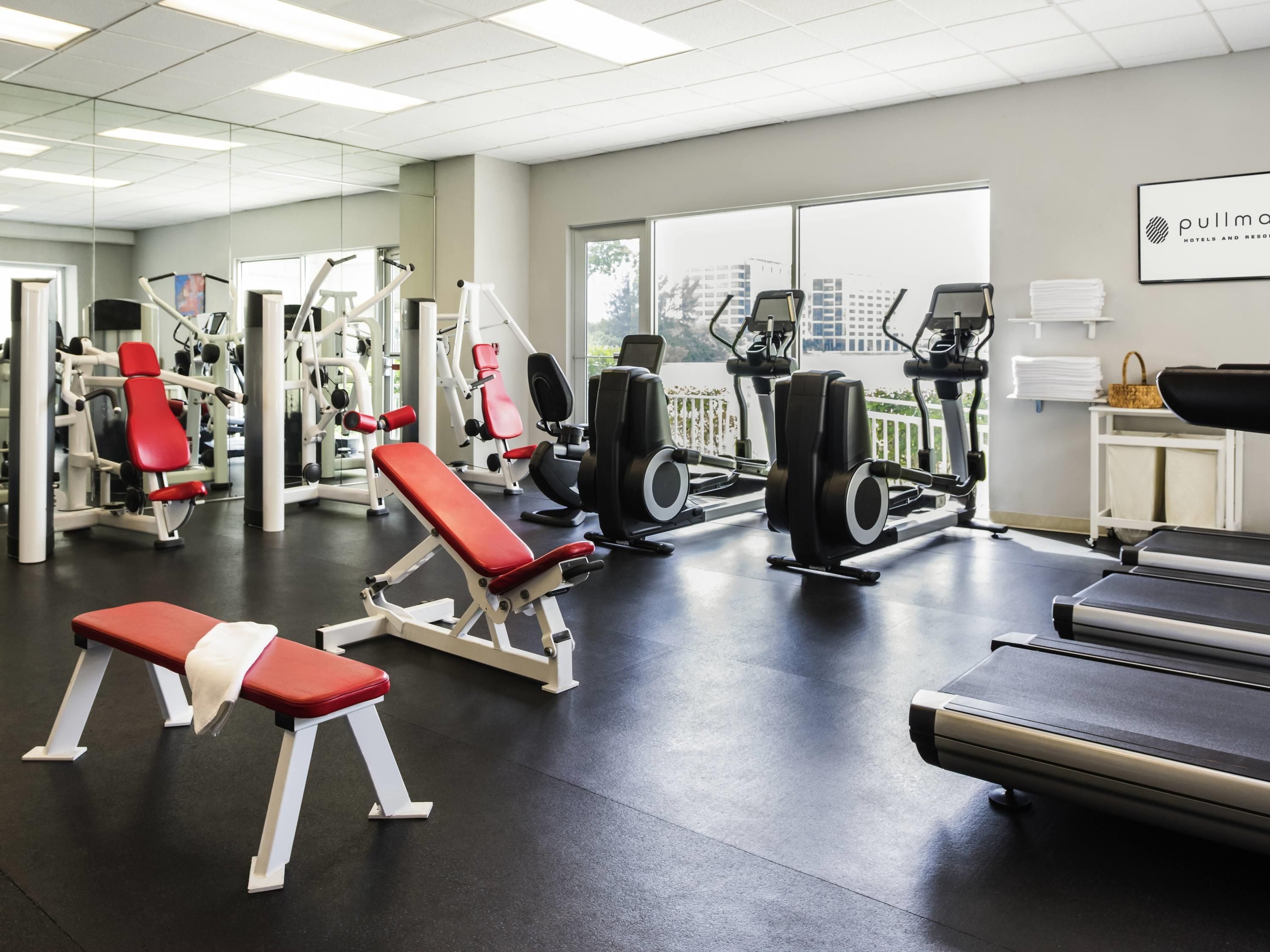 A gym with various exercise equipment, a bench, and a treadmill.