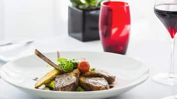 A plate of food with a glass of red wine and a plant in the background.