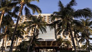 A hotel with a modern facade, palm trees, and a well-lit entrance. - Pullman Miami Airport (Miami)