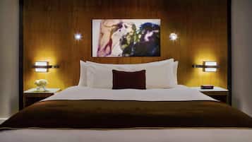 Une chambre d’hôtel avec un grand lit, deux tables de chevet avec des lampes et un tableau au-dessus du lit.